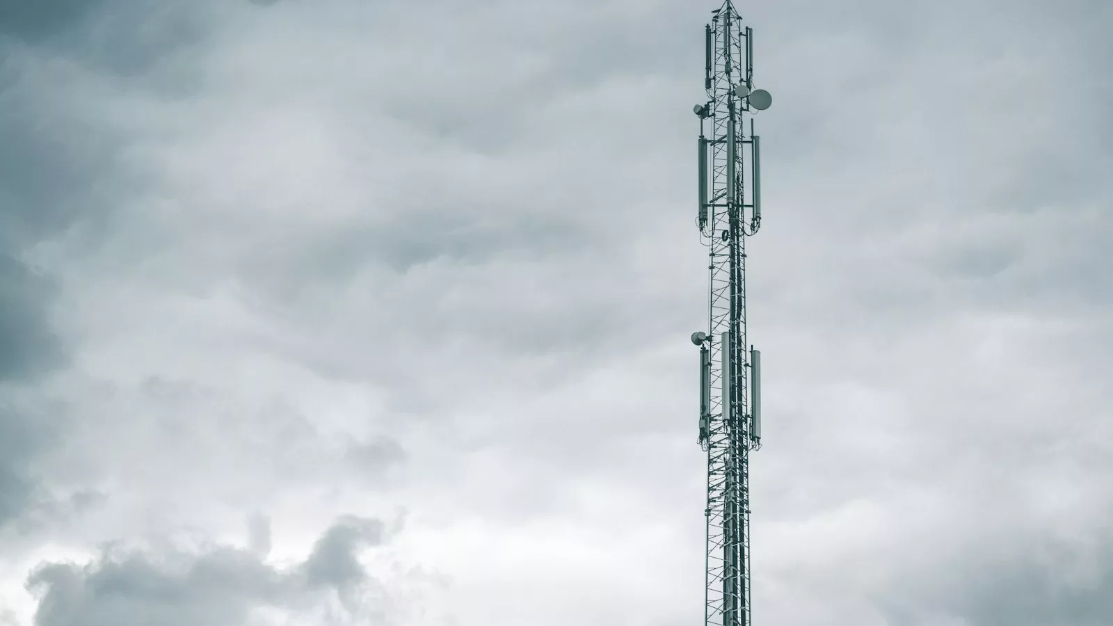 Gray radio tower under the cloudy sky during daytime