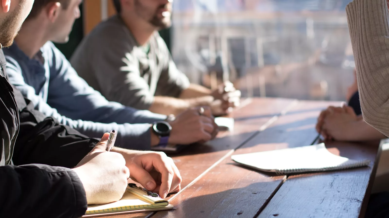 People sitting on chair in front of table while holding pens during daytime
