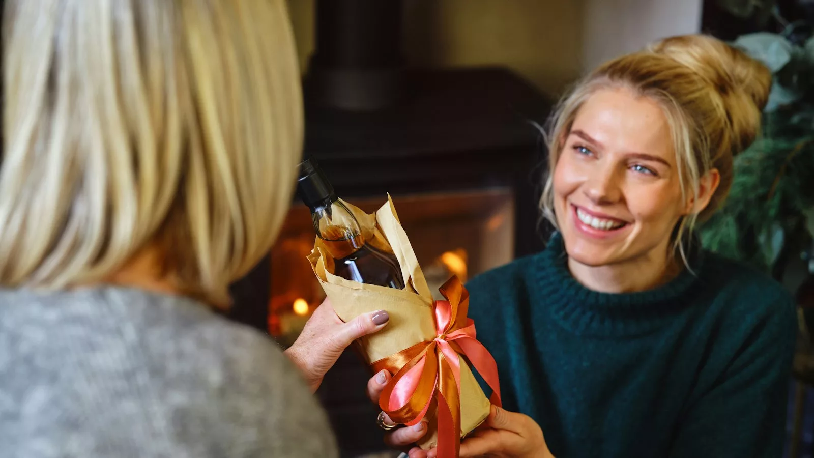 A woman holding a wrapped present in front of another woman