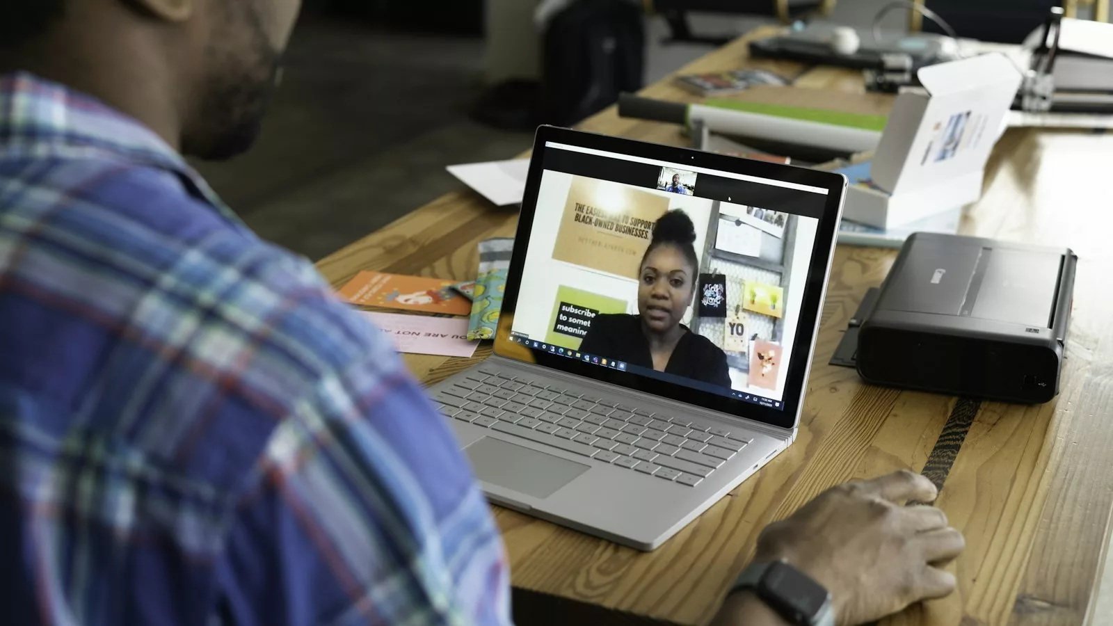 Man in blue and white plaid shirt using macbook pro