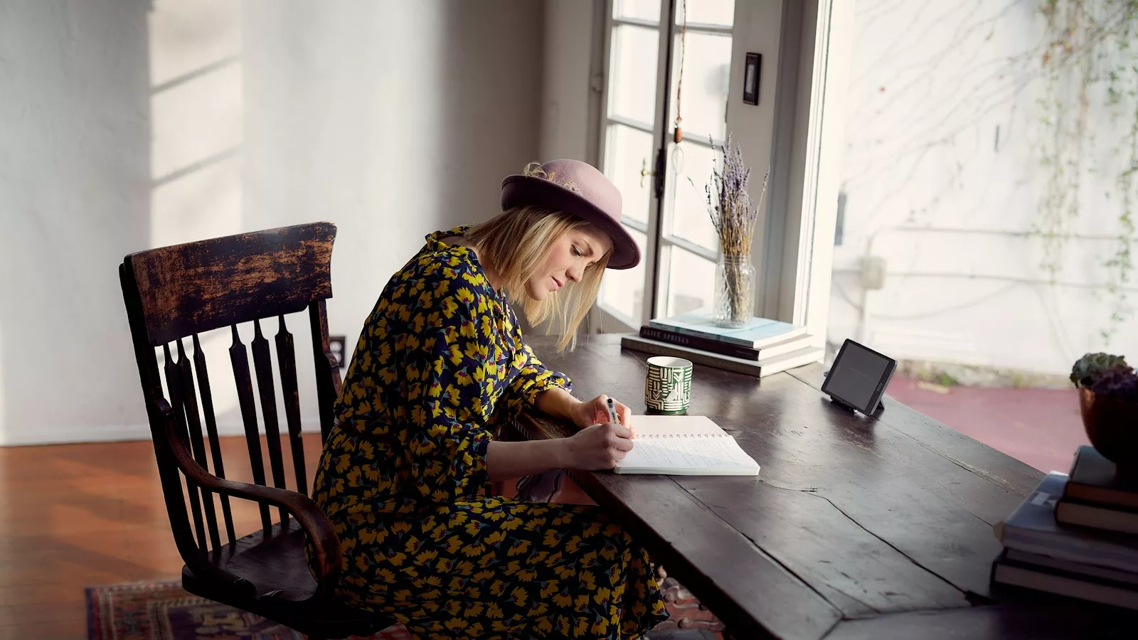 Woman in yellow and black floral dress sitting on brown wooden chair