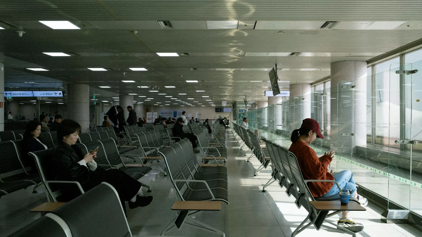 People waiting in a modern airport lounge by large windows